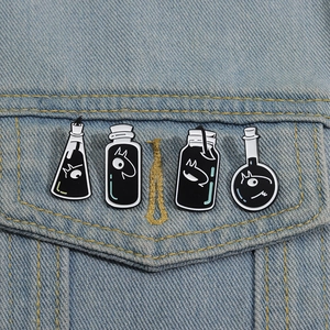 Set of four black and white enamel potion pins pinned to a blue denim jacket pocket