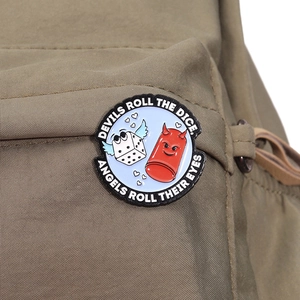 Enamel badge with dice design pinned to a khaki canvas backpack as a creative accessory