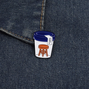 Close-up of funny Stool Sample enamel pin with clear jar design on denim fabric