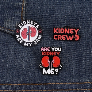 Macro view of three creative cartoon kidney enamel pins on blue denim fabric background