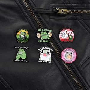 Vue détaillée de six épingles en émail de grenouille de dessin animé sur veste en cuir noir