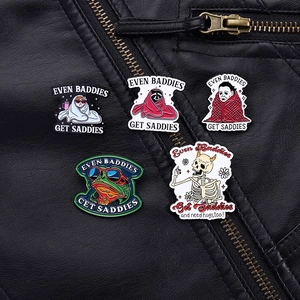 Detail view of frog and skull enamel pins on black leather with baddie slogans