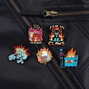Fünf Punk-Emaille-Pins mit Flammen-Totenkopf und Katze auf einer schwarzen Lederjacke im Detail