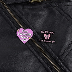 Macro view of pink heart and bow enamel pins with quotes on a black leather jacket