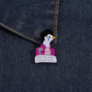 Detail of a purple dove enamel pin with lyrics on blue denim background fabric