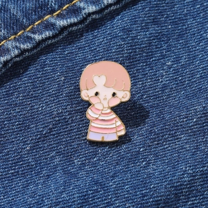 Cute cartoon boy enamel pin with orange hair on blue denim jacket fabric background