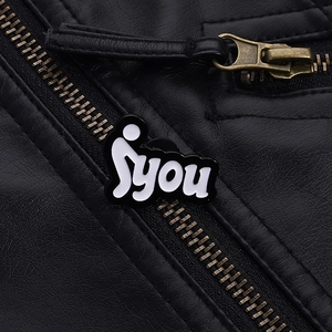 Macro detail of artistic enamel pin with unique fyou lettering on a black leather jacket