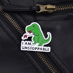 Dettaglio della spilla a forma di dinosauro T-Rex verde su giacca di pelle nera