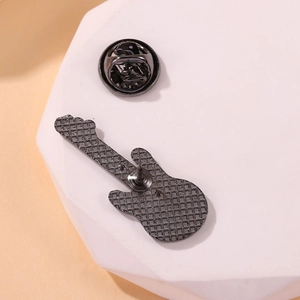 Macro view of guitar-shaped brooch back with textured metal and secure butterfly clasp