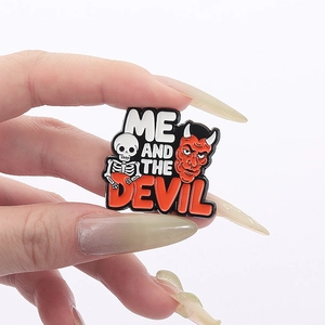 Close-up of enamel pin featuring a skull and devil design with Me and the Devil text