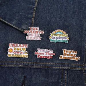 Set di cinque spille smaltate con frasi motivazionali su tessuto di jeans