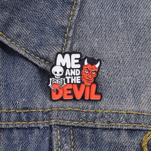 Close-up of Me and the Devil enamel pin with skull and devil on denim jacket