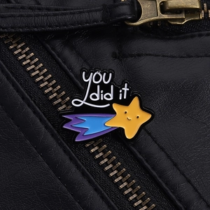 Detail of cute shooting star enamel pin with 'YOU did it' text on black leather jacket