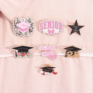 Detailed close-up of pink enamel graduation pins set on a denim jacket for class of 2025