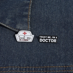 Close-up of nurse hat and doctor slogan enamel pins pinned on blue denim fabric