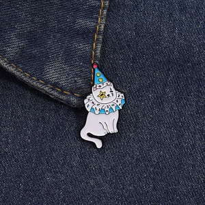 Gros plan sur l'épingle en émail chat de cirque blanc avec chapeau de fête sur denim
