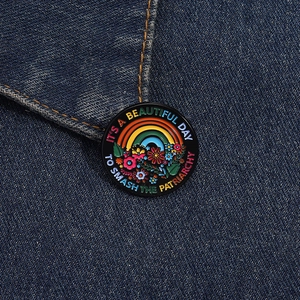 Close-up of enamel rainbow flower badge with feminist slogan on denim jacket