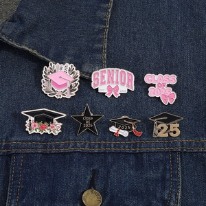 Detail of seven enamel graduation pins featuring Class of 2025 motifs on denim fabric