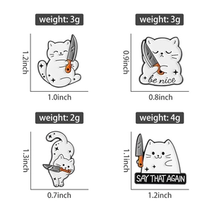 Detailansicht von weißen Katzen-Emails-Pins mit Messern und 'be nice' sowie 'SAY THAT AGAIN'