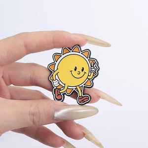 Detailed close-up of a smiling cartoon sun enamel pin held to show size and quality
