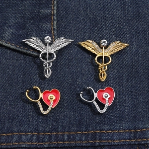 Détail des broches médicales caducée et stéthoscope avec des cœurs en émail rouge