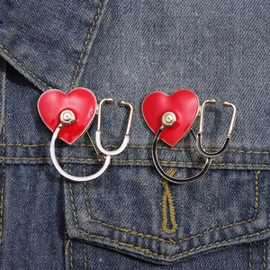 Détail de broches stéthoscope et cœur rouge sur la poche d'une veste en jean bleue