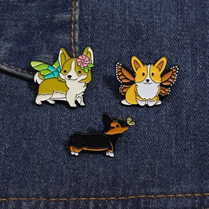 Gros plan détaillé de trois pin's en émail corgi avec des ailes de papillon sur denim