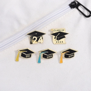 Detail view of 2024 graduation cap enamel pins showing BSC, MHA, and MPH degree emblems