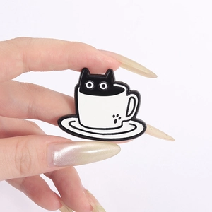 Vue rapprochée du pin's émaillé chat noir dans une tasse à café blanche avec patte