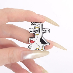 Close-up of seagull enamel pin held in hand showing size and WINE! lettering detail