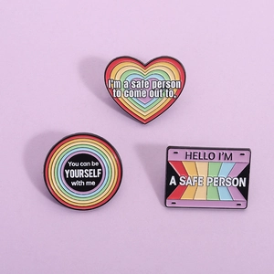 Set of three rainbow enamel pins with LGBTQ+ support quotes on a light purple background