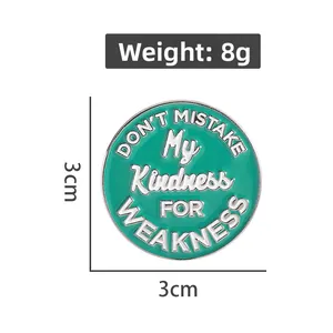 Detail showing 3cm round enamel pin with Don't Mistake My Kindness for Weakness quote