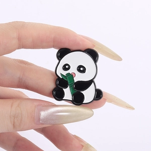 Close-up of a cute cartoon panda enamel pin holding bamboo on a white background