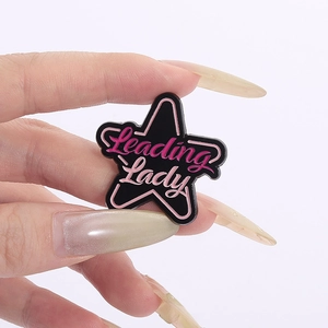 Macro shot of a star-shaped enamel brooch with Leading Lady text and pink borders