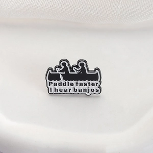 Black and white enamel pin featuring silhouettes of rowers with funny quote engraving