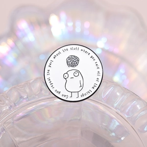 Detail view of round enamel pin with black cartoon figure and iridescent glass background