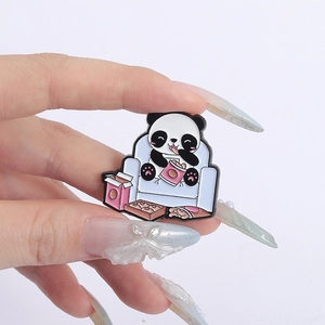 Close-up of cute panda enamel pin featuring a panda eating snacks on a blue sofa