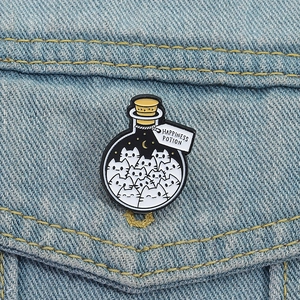 Cute white cat potion bottle enamel pin with Happiness Potion tag on blue denim jacket