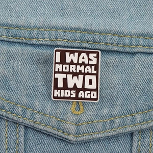I Was Normal Two Kids Ago enamel pin on denim jacket showcasing funny parenting quote