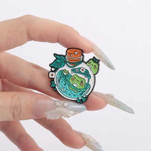 Gros plan d'une épinglette en émail de potion de grenouille mignonne avec étoiles et lune