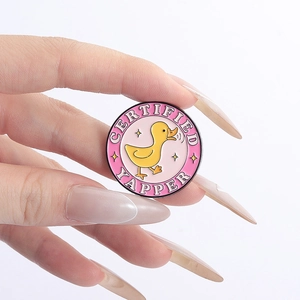 Gros plan détaillé d'une broche en émail rose avec canard jaune et texte humoristique