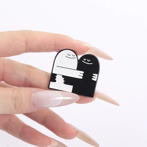 Close-up of heart-shaped enamel pin featuring cute cartoon characters in a hug