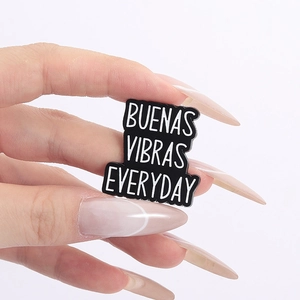 Close-up of Buenas Vibras Everyday enamel pin badge held in hand showing size details