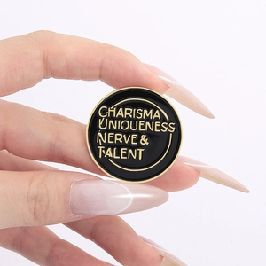 Detail of hand-held enamel pin badge with gold text on black metal surface