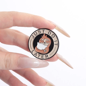 Detail of round sloth enamel pin with Just Do It Later slogan held by fingers