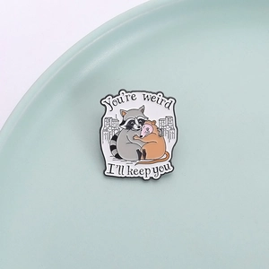 Cute enamel raccoon and opossum hug brooch with 'You're weird, I'll keep you' text