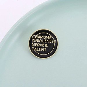 Round enamel pin with 'Charisma Uniqueness Nerve & Talent' text on a mint green plate