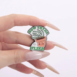 Macro detail of enamel thyme pin featuring 'How Thyme Flies' pun text in hand