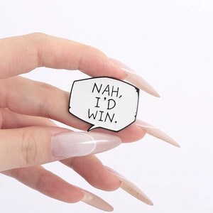 Close-up of manga speech bubble enamel pin with 'NAH, I'D WIN' text held by hand