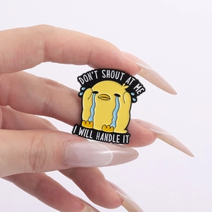 Close-up of a cartoon crying duck enamel pin with Don't Shout At Me text on a hand